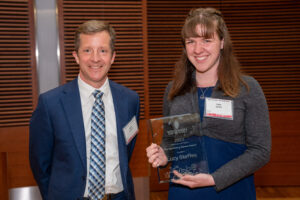 a man on the left with a woman on the right holding a clear glass plaque