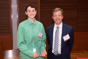 a man on the right with a person on the left holding a clear glass plaque