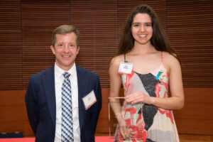 a man on the left with a woman on the right holding a clear glass plaque
