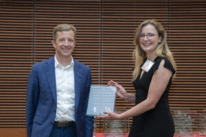 a woman on the right holds a glass plaque and stands next to a man