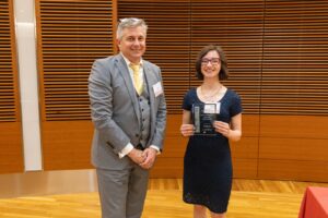 two people stand, one is holding a glass plaque