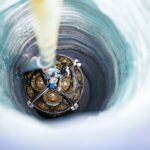 a sphere with lots of wires and such inside of it is lowered into a hollowed out tunnel in ice